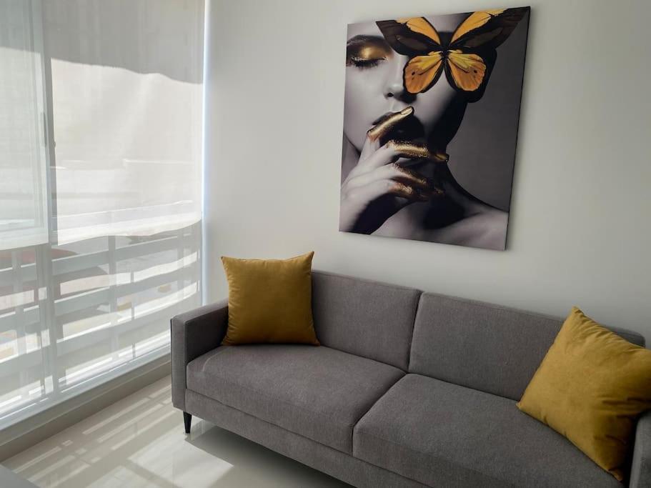 un sofá en la sala de estar con una mariposa en la pared en Nuevo a 10 minutos de Buenavista, en Puerto Colombia