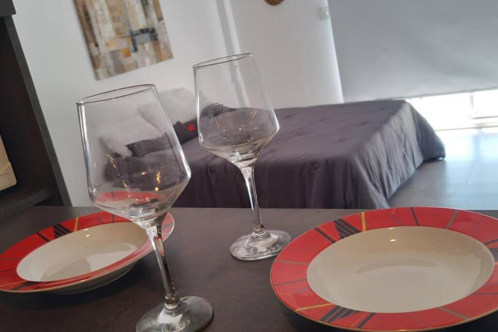 two wine glasses and a plate on a table at Exclusivo Monoambiente Moderno by G&A Rent (409) in Ezeiza