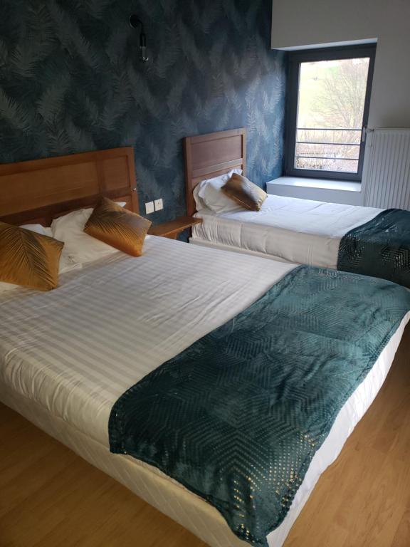 2 łóżka w pokoju hotelowym z oknem w obiekcie Restaurant Hôtel du Vercors w mieście Saint-Martin-en-Vercors