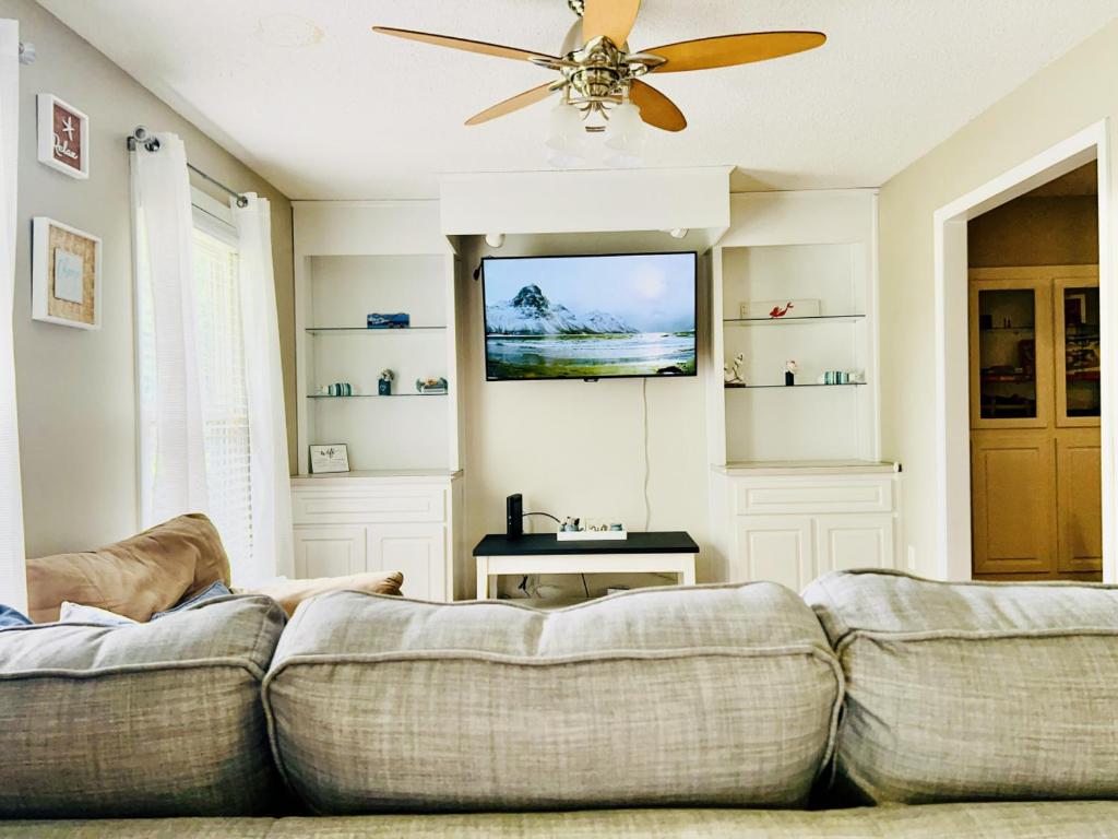uma sala de estar com um sofá e uma ventoinha de tecto em Cozy Family Retreat with Spa Bath Fenced Yard em New Bern