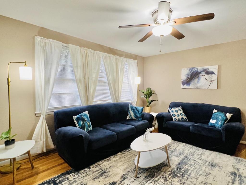 - un salon avec deux canapés bleus et un ventilateur de plafond dans l'établissement Cozy 4 bedroom Cottage by Duke Raleigh Hospital, à Raleigh
