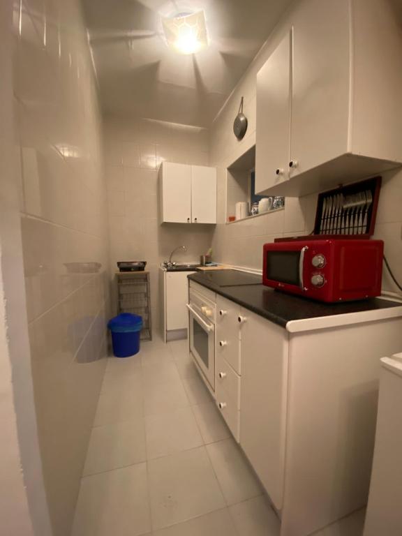 małą białą kuchnię z czerwonym urządzeniem na ladzie w obiekcie Apartamento Callejon del Beso w Sewilli