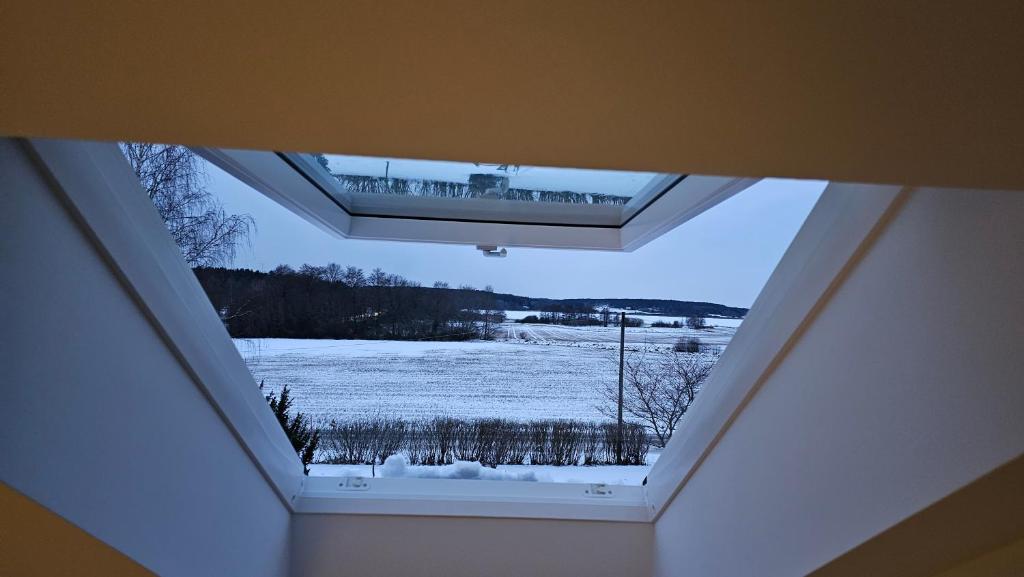 uma clarabóia numa casa com uma janela coberta de neve em Attic floor with views over fields and sea em Sigtuna