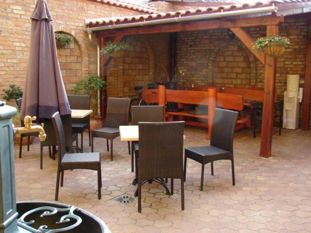 un patio con mesa, sillas y sombrilla en Arany Elefánt szálláshely en Esztergom