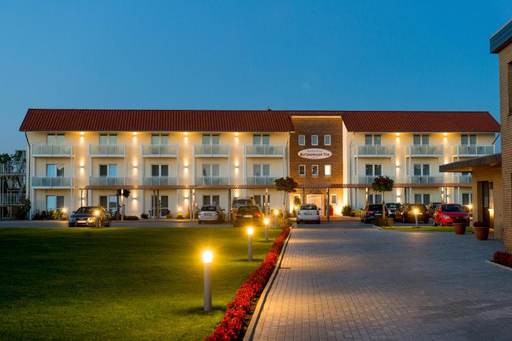 a large building with cars parked in front of it at Komforthotel Butjadinger Tor in Nordenham