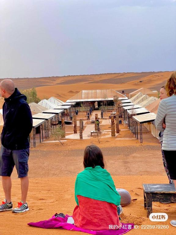 a group of people standing around a building in the desert at Akabar Luxury Desert Camp in Merzouga