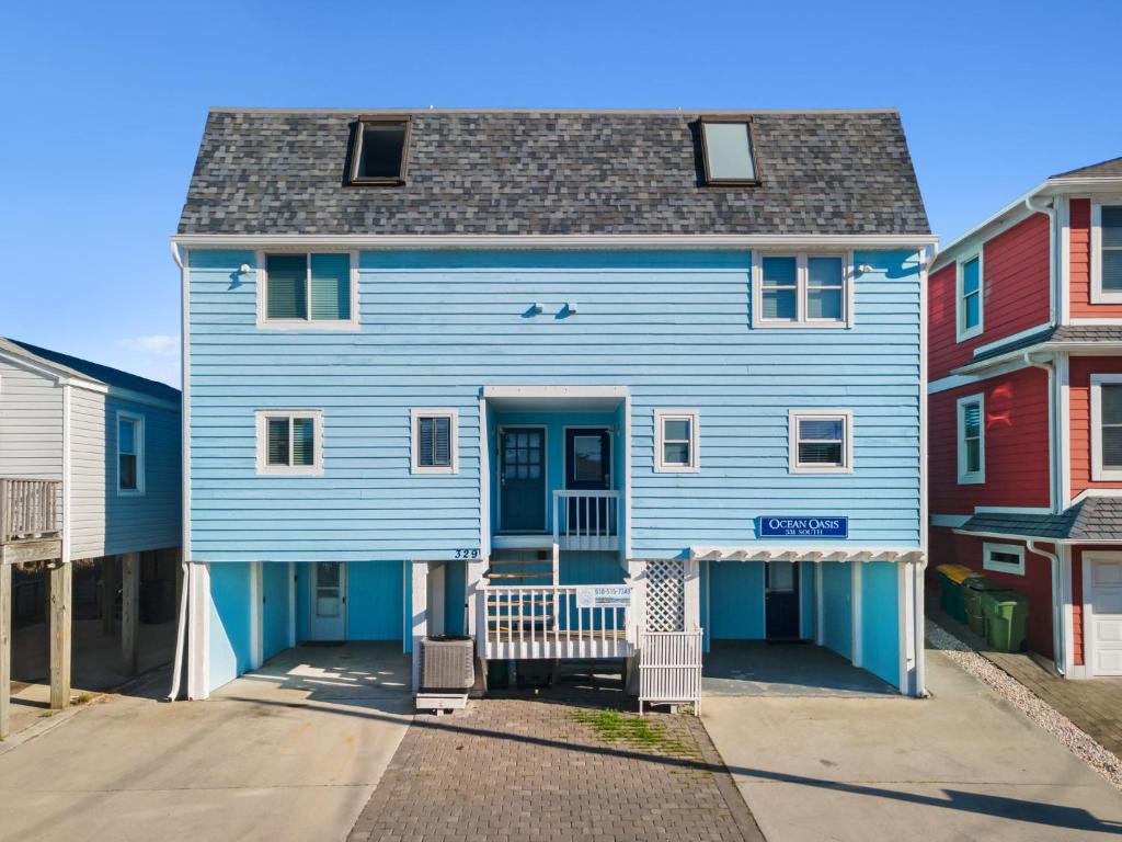 a blue house on a street with colorful houses at Pure Paradise Kure Beach, Ocean front, Pool coming soon! in Kure Beach