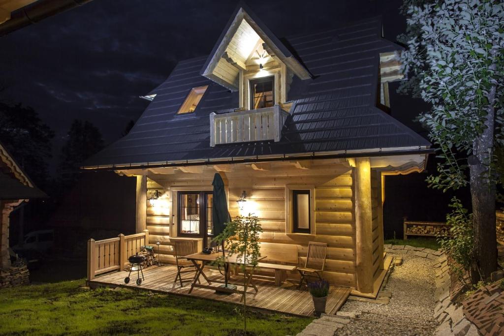 a tiny house with a deck at night at Maki Domki Regionalne in Witów