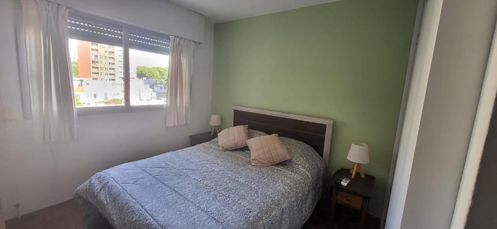 um quarto com uma cama com duas almofadas e uma janela em apto 1 dorm sobre Ellauri em Montevidéu