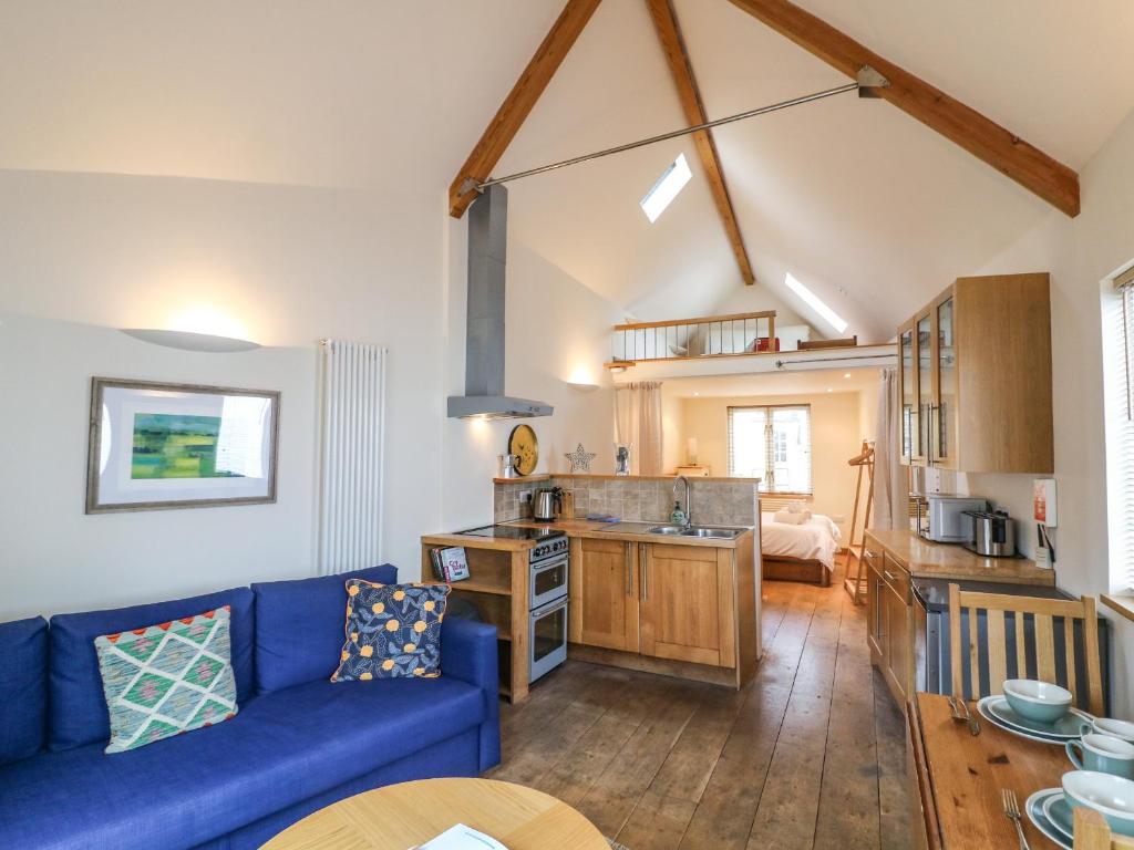 a living room with a blue couch and a kitchen at The Loft Cottage in Totnes