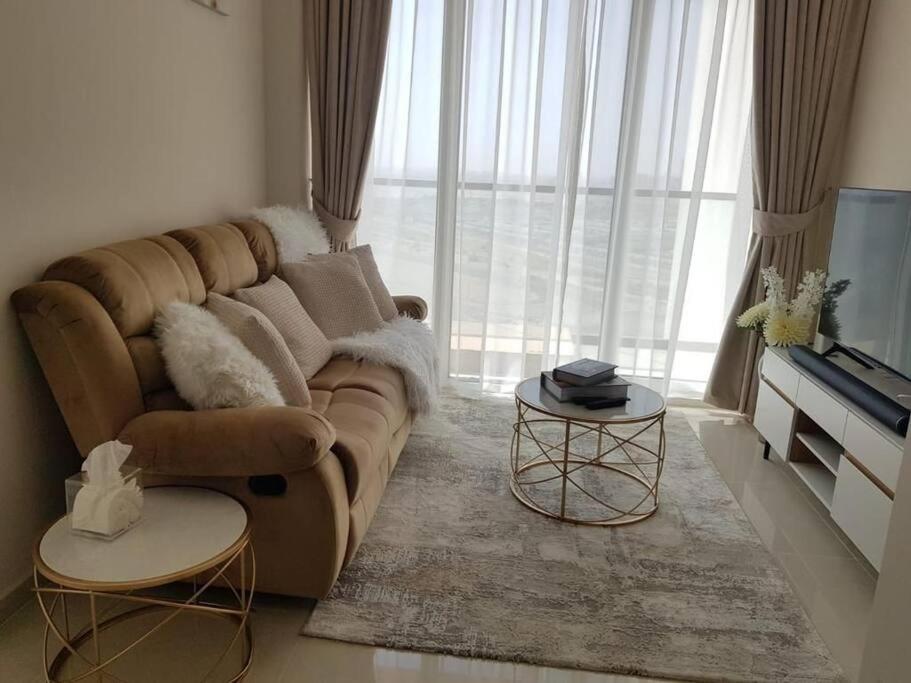 a living room with a brown couch and a large window at Cosy 1 bedroom in Damac Hills in Dubai