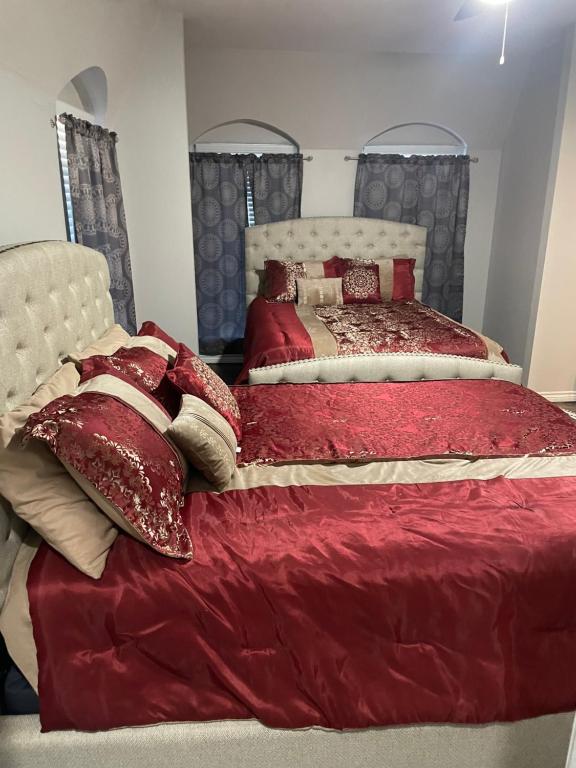 sypialnia z 2 łóżkami z czerwonymi kocami i poduszkami w obiekcie The Ramas w mieście Houston