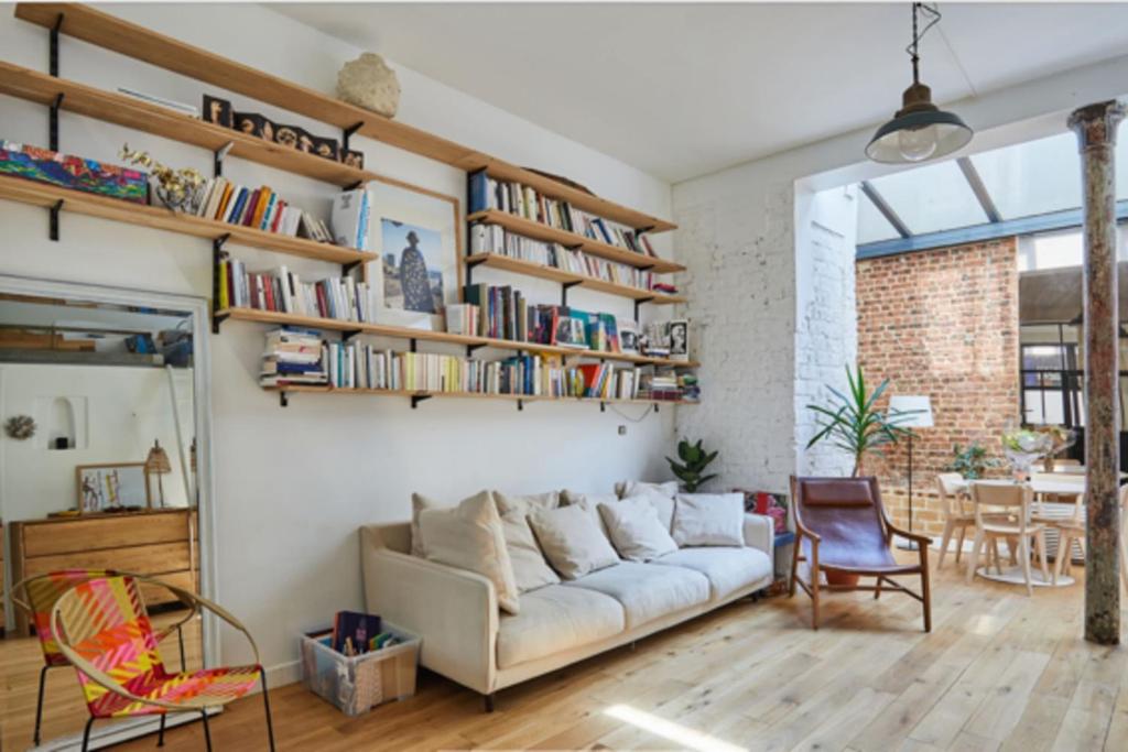 uma sala de estar com um sofá e estantes em 60 m nest near the Atelier des Lumières em Paris