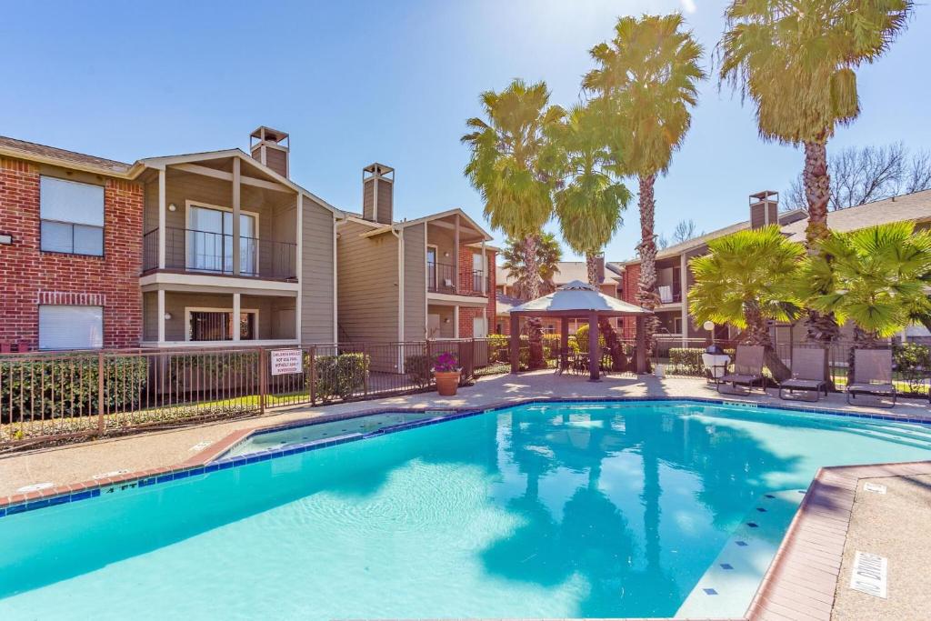 a swimming pool in front of a house with palm trees at The Val's Place in Houston