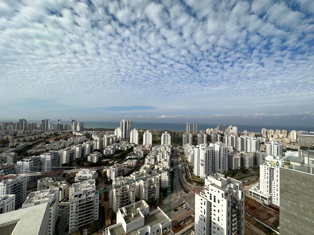 a city skyline with buildings and a cloudy sky at SkyHostel_32Floor in Netanya