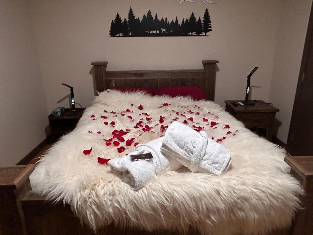 a bed with a white blanket and red flowers on it at Romantic Luxury Retreat with Private Sauna & Spa, Pet Friendly, Elkside Hideout B&B in Canmore