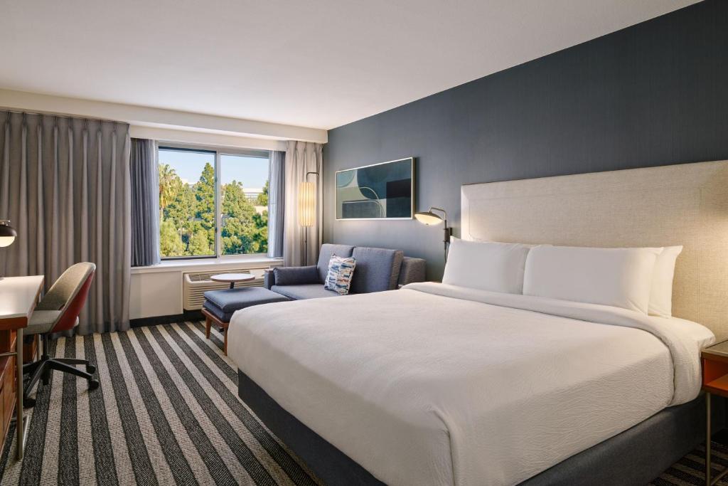 Courtyard by Marriott Los Angeles Westside في لوس أنجلوس: غرفة فندقية بسرير كبير وكرسي