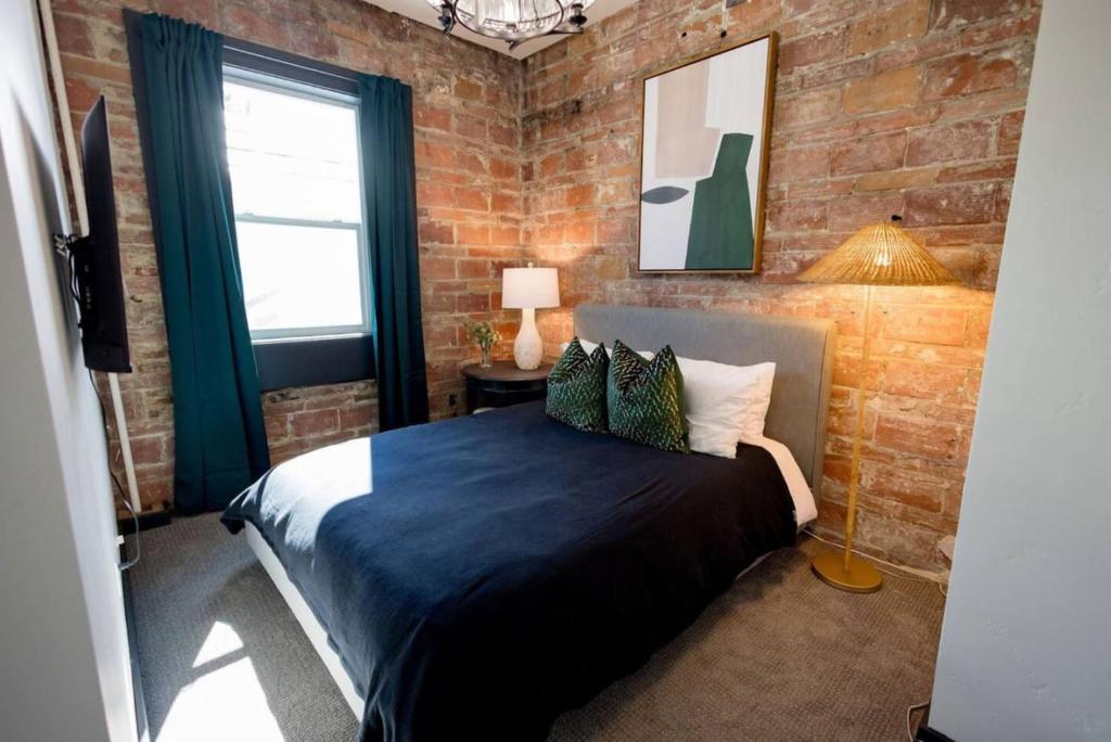 a bedroom with a bed and a brick wall at Speakeasy Queen Suite (Rm 7) in Nevada City