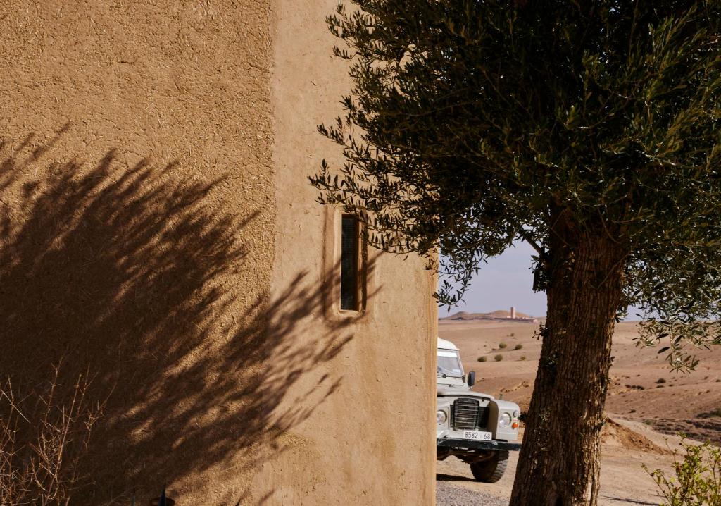 a truck parked next to a building with a tree at Agafay Desert Hotel in El Karia