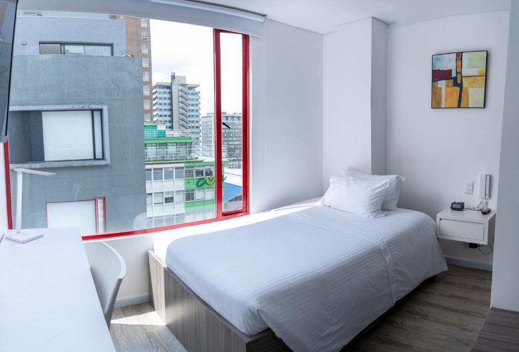 a bedroom with a white bed and a large window at Esstudia 17-4 in Bogotá