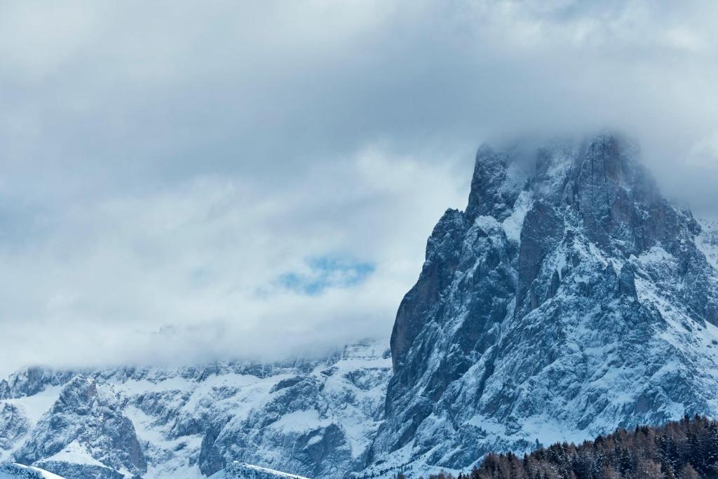 una montaña cubierta de nieve y nubes en COMO Alpina Dolomites, en Alpe di Siusi