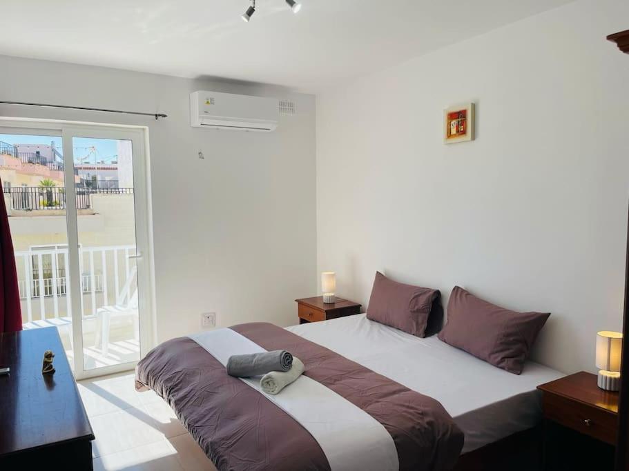 a bedroom with a large bed with purple pillows at Coral Cove Comfort Room 1 in St Paul's Bay