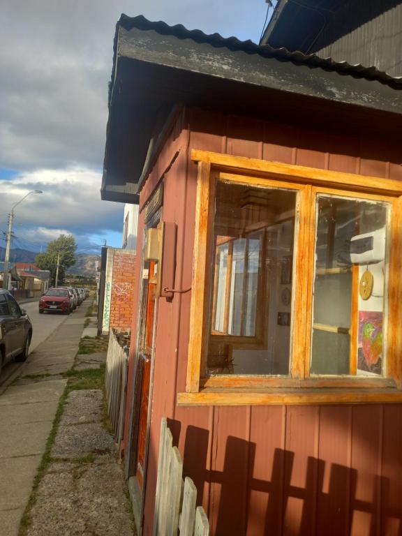 un bâtiment rouge avec une fenêtre sur une rue dans l'établissement Isaac house, à Puerto Natales