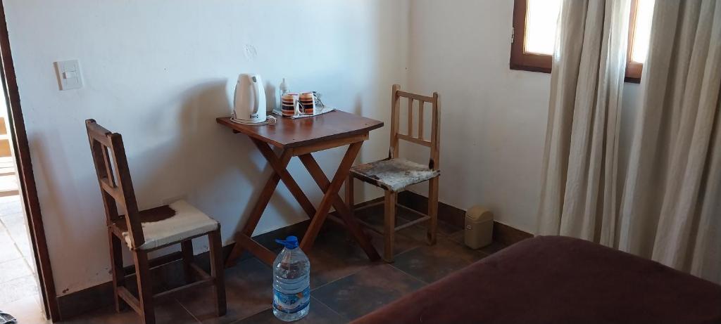 einen kleinen Tisch mit 2 Stühlen und eine Flasche Wasser in der Unterkunft Cabañitas EL REPOSO HUMAHUACA in Humahuaca
