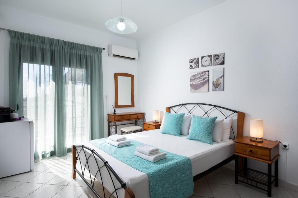 a bedroom with a white bed with blue pillows at Kentrikon Rooms in Limenaria