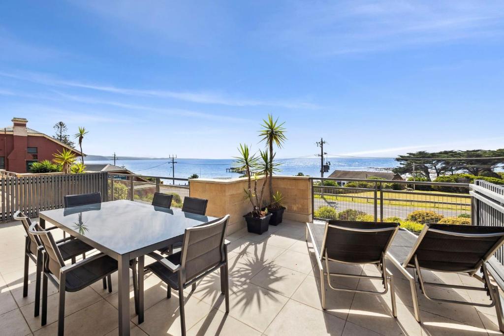um pátio com uma mesa e cadeiras e o oceano em Apartment 12 Pacific Apartments em Lorne