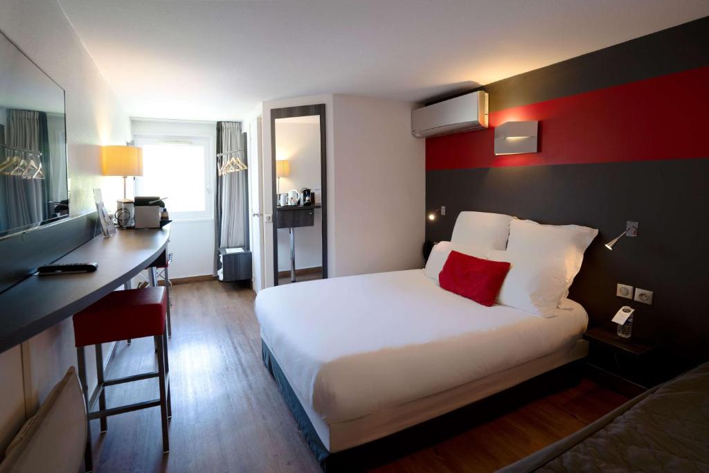 ビュクにあるベストウエスタン ザ ホテル ヴェルサイユのベッドとデスクが備わるホテルルームです。