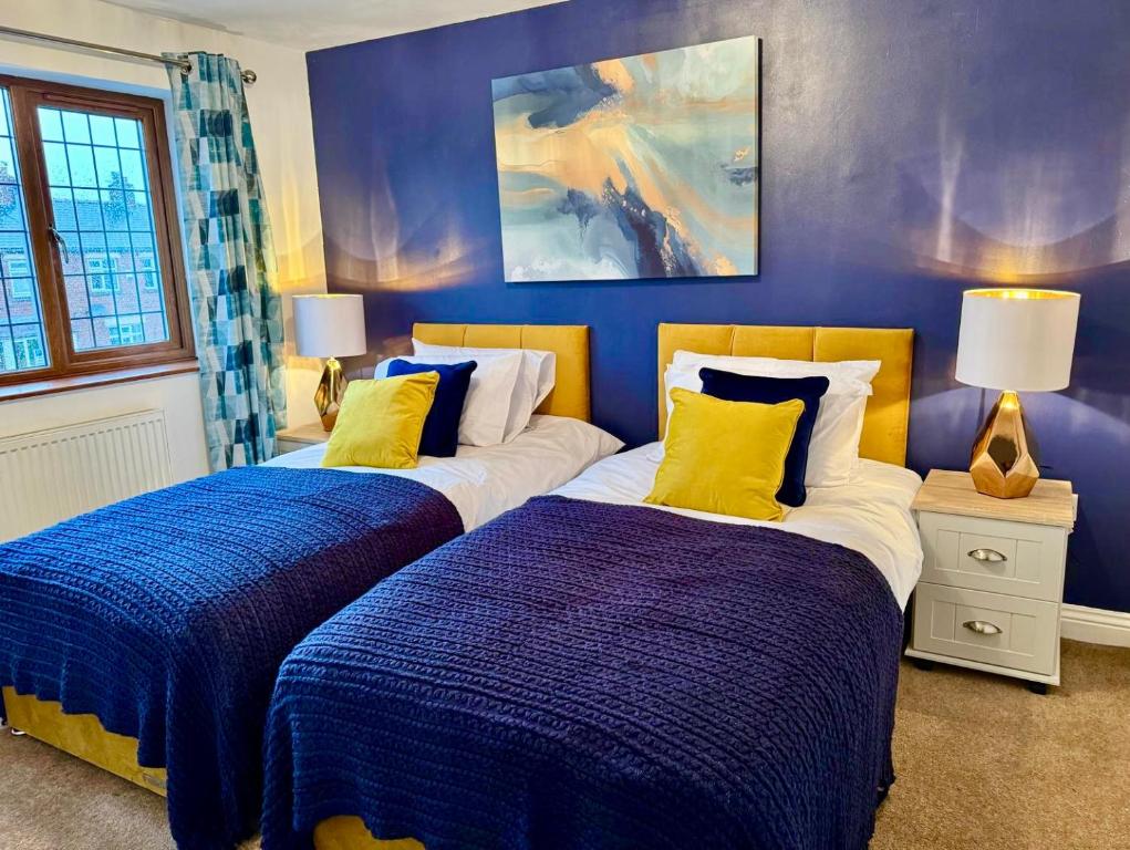 - 2 lits dans une chambre avec des murs bleus et des oreillers jaunes dans l'établissement 3br House Ossett-Wakefield, Free Parking 3 cars Wi Fi Long stays, à Wakefield