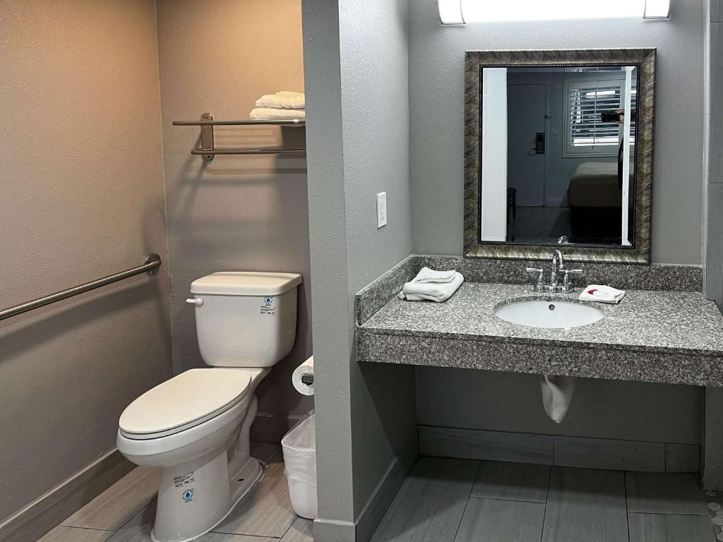 a bathroom with a toilet and a sink with a mirror at Studio 6 Artesia CA in Artesia
