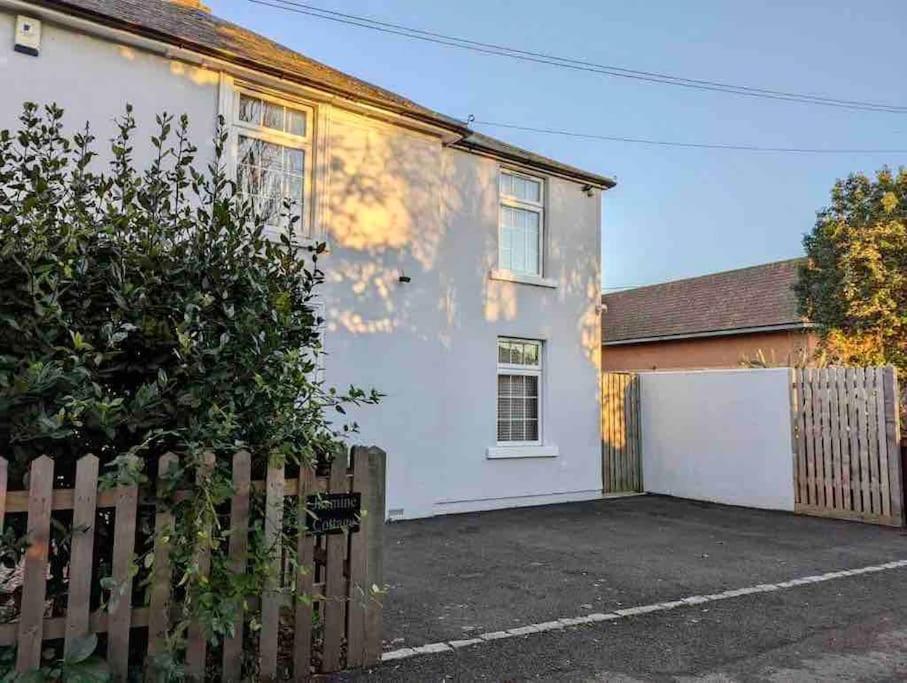 una casa blanca con valla y entrada en Little Knapp Cottage, East of Church Road, Chichester, West Sussex PO19 7YH, en Chichester