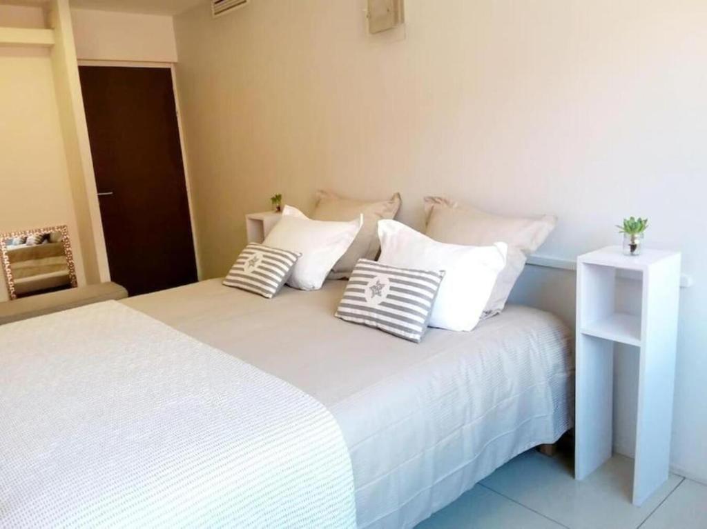 a bedroom with a white bed with pillows on it at Le Palace climatisé au centre-ville - Piscine - Proximité Plage et Espagne in Perpignan