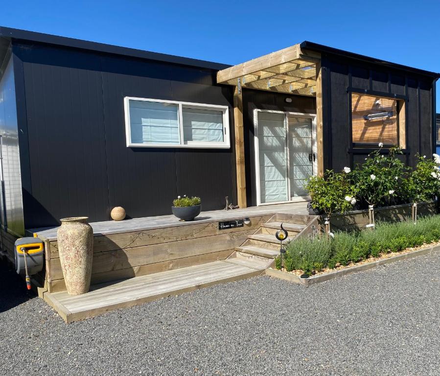 a black tiny house with a wooden porch at Haven On Tau in Ohakune