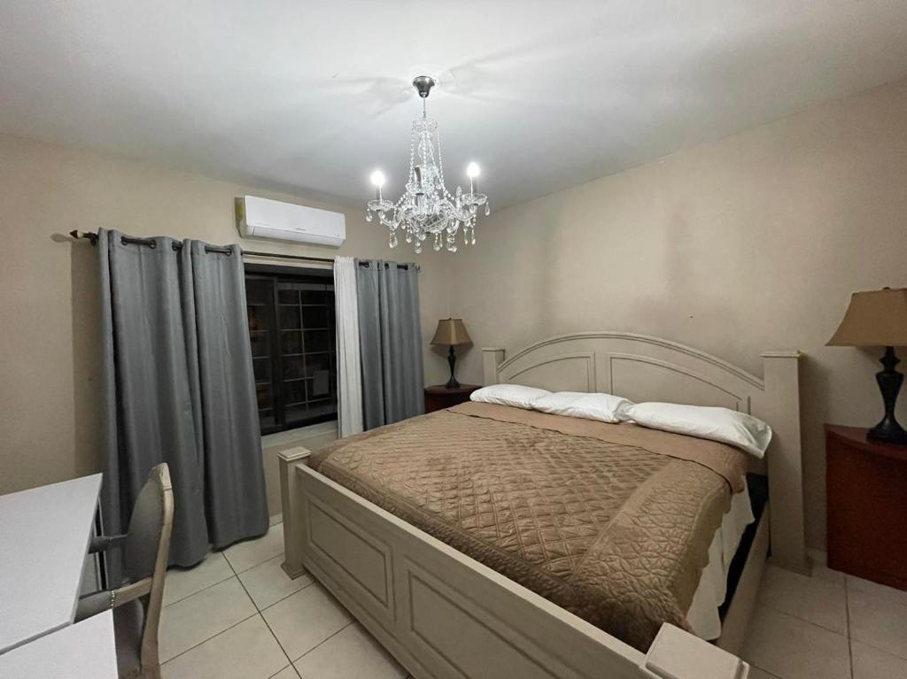 sypialnia z dużym łóżkiem i żyrandolem w obiekcie Quinta Vela Hotel w mieście Tegucigalpa