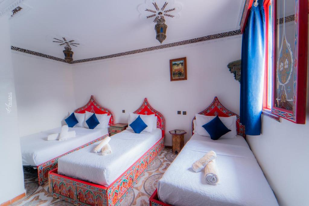 Hotel Chefchaouen في شفشاون: سريرين في غرفة مع وسائد حمراء وزرقاء