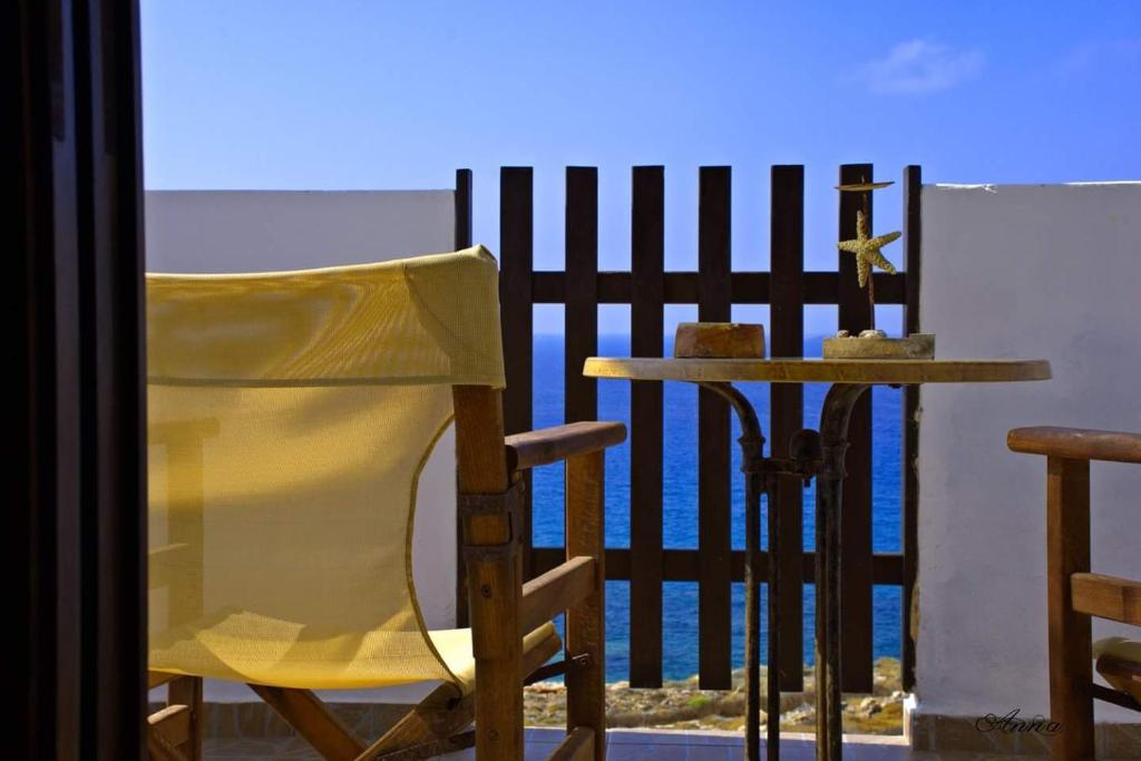 a yellow chair sitting next to a table and a fence at Meltemi Studios in Frý