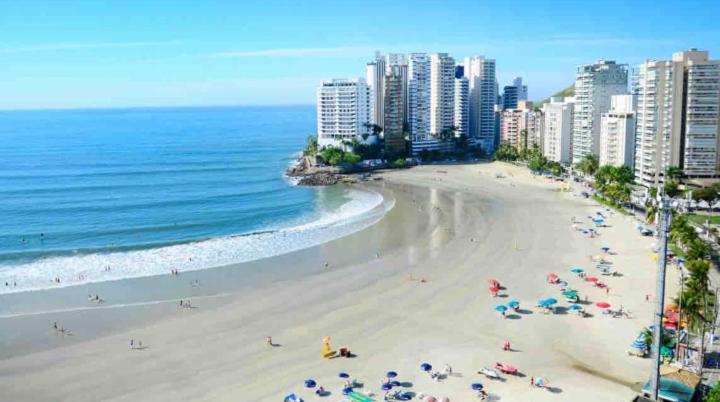 a beach with people and the ocean and buildings at Suite Guarujá in Guarujá