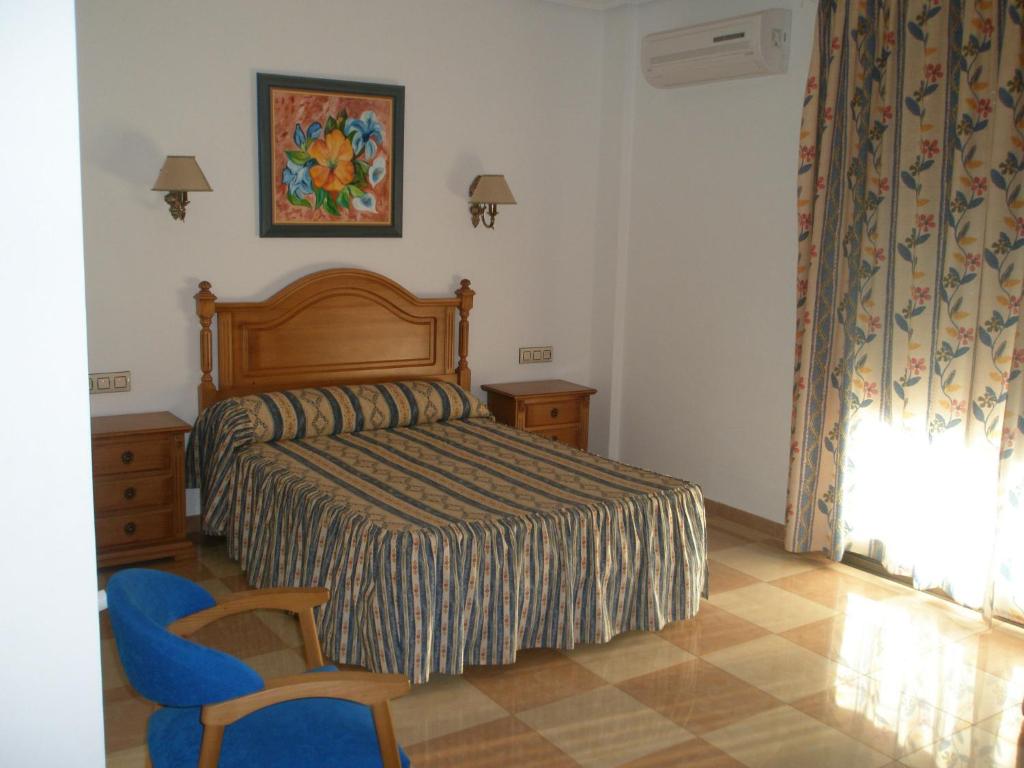 sypialnia z łóżkiem i niebieskim krzesłem w obiekcie Hostal Los Rosales w mieście Alcaraz