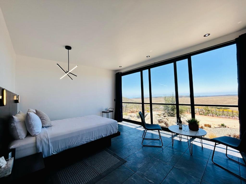 - une chambre avec un lit, une table et une grande fenêtre dans l'établissement NUMA Wine Suites, à Ensenada