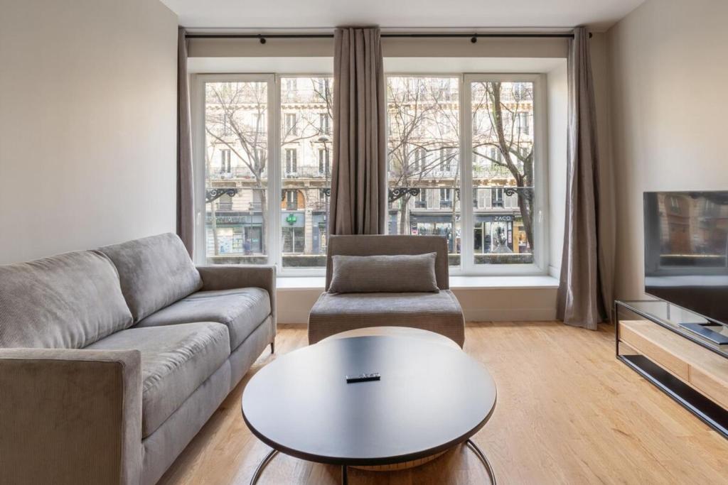 un salon avec un canapé et une table dans l'établissement Beautiful Minimalist 1BD Apartment near Montmartre, à Paris