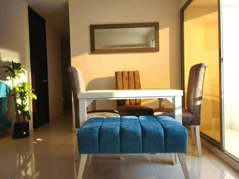 a dining room with a table and a blue ottoman at Apartamento con excelente vista in Cúcuta