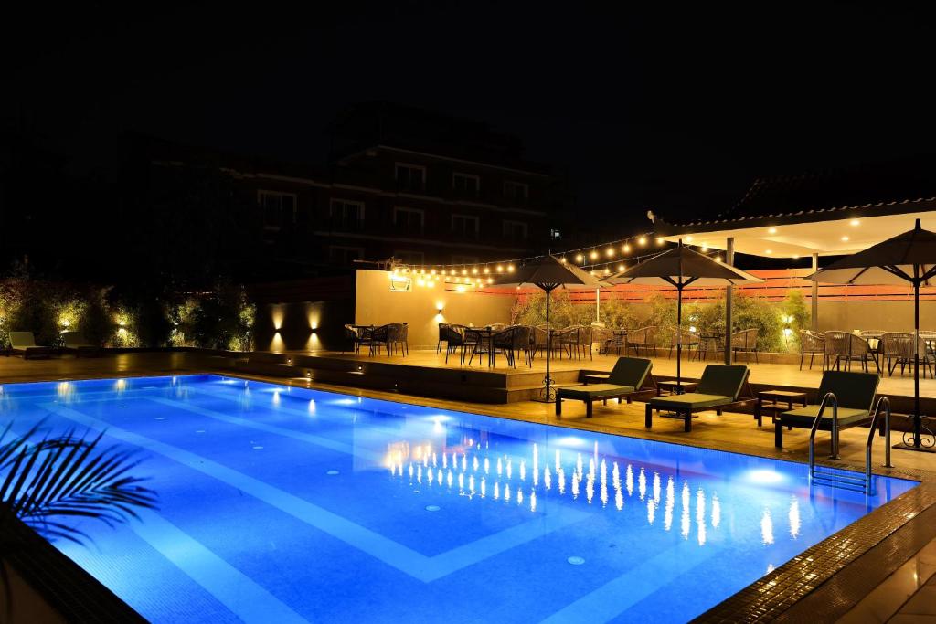 a swimming pool at night with tables and chairs at Hotel Dolmaling in Kathmandu
