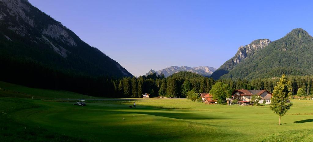 um campo de golfe verde com montanhas ao fundo em Ferienwohnungen Ramslerhof em Ruhpolding