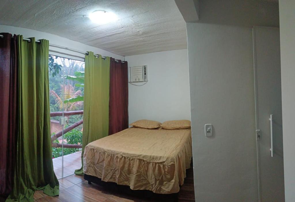 a bedroom with a bed and a window with curtains at Casa de Praia in Angra dos Reis