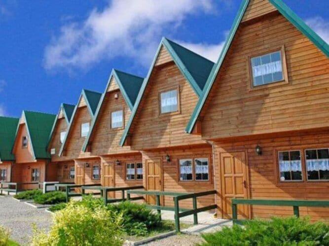 un grand bâtiment en bois avec des bancs devant lui dans l'établissement Cozy holiday home, Sarbinowo, à Sarbinowo