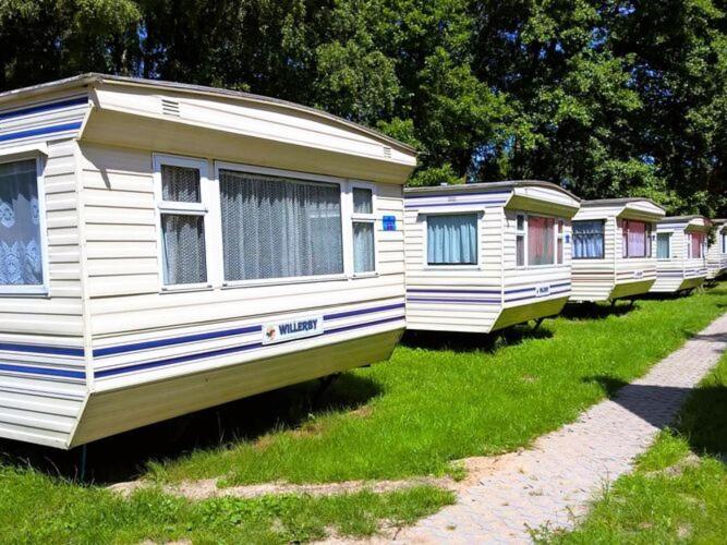 une rangée de mobile homes garés dans l'herbe dans l'établissement Dutch houses for 4 people, close to the sea, à Łazy