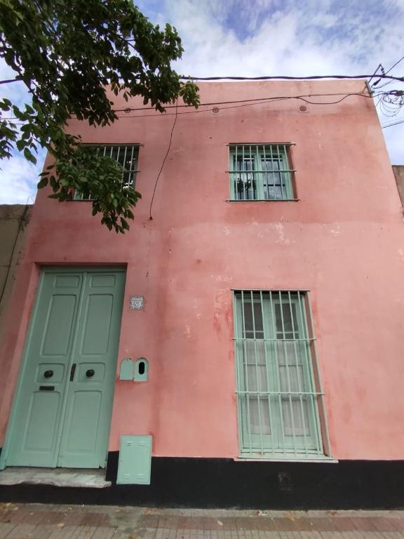 un edificio rosa con dos ventanas y una puerta en CasaLins en Chascomús